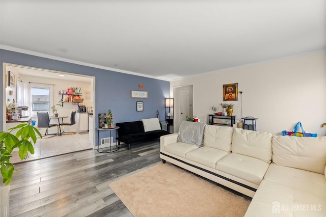 living area featuring visible vents, crown molding, baseboards, and wood finished floors