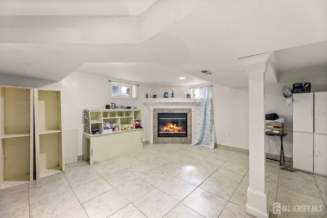 living area featuring light tile patterned floors, baseboards, visible vents, and a tile fireplace