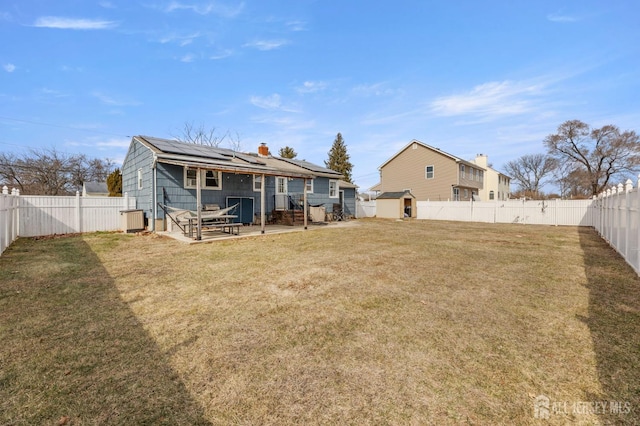 back of property featuring a patio area, roof mounted solar panels, a lawn, and a fenced backyard