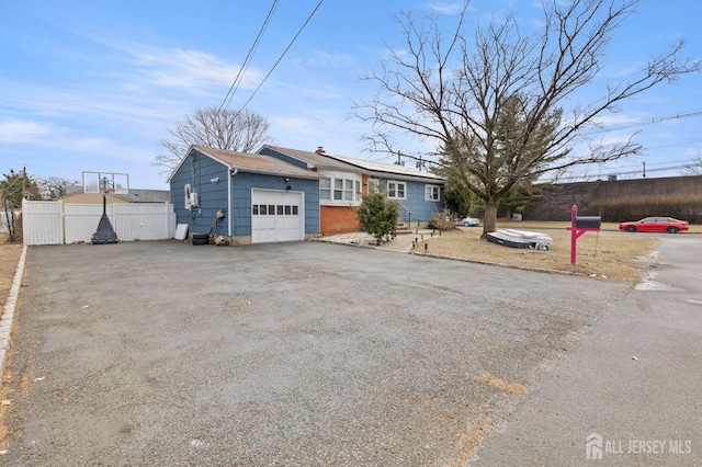 ranch-style house with aphalt driveway, an attached garage, and fence