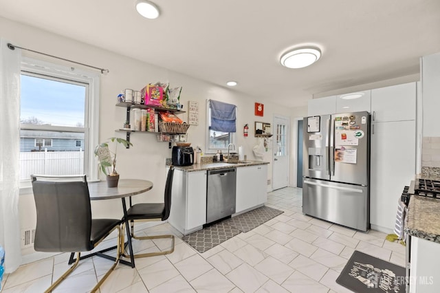 kitchen featuring stone counters, a sink, stainless steel appliances, white cabinets, and tasteful backsplash