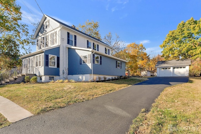 view of side of home featuring a lawn, a garage, and an outbuilding