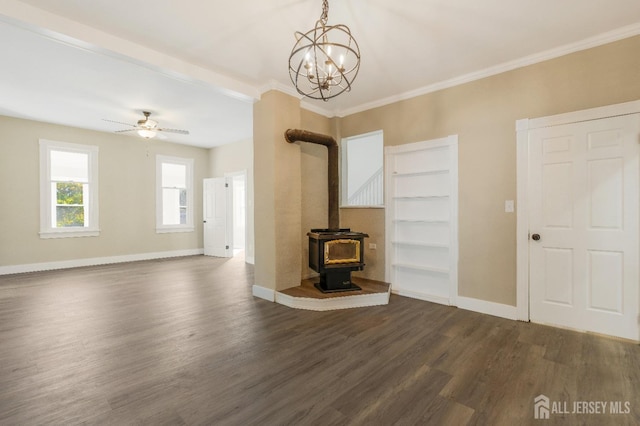 unfurnished living room featuring a wood stove, ceiling fan with notable chandelier, dark hardwood / wood-style floors, and ornamental molding