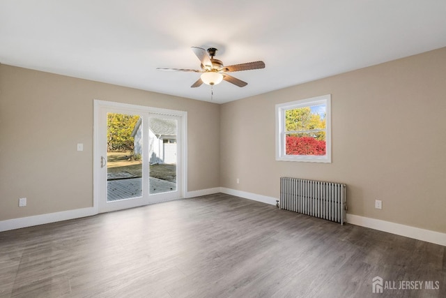 empty room with hardwood / wood-style floors, ceiling fan, and radiator