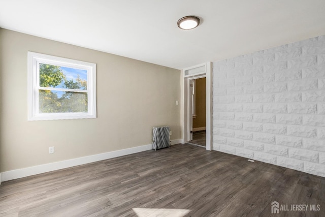 empty room featuring hardwood / wood-style floors and radiator heating unit