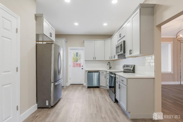 kitchen featuring backsplash, sink, stainless steel appliances, and light hardwood / wood-style floors