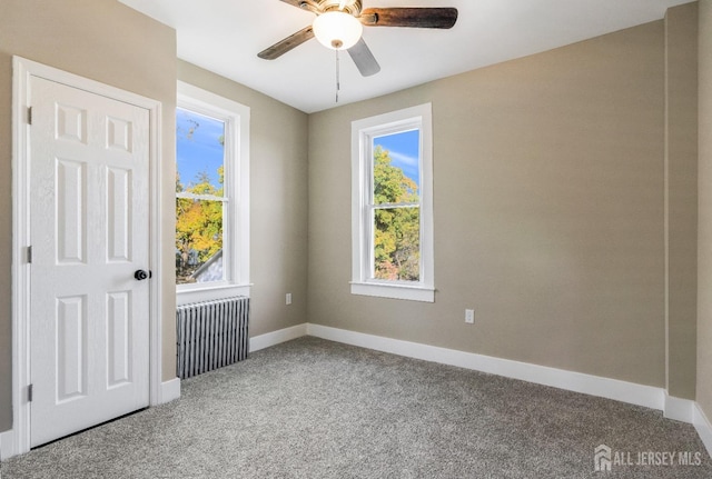 empty room with carpet flooring, radiator heating unit, plenty of natural light, and ceiling fan