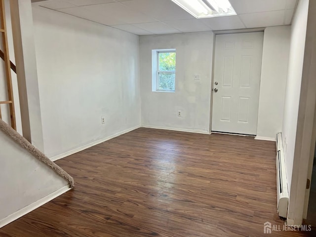 unfurnished room with a drop ceiling, dark wood-type flooring, and a baseboard radiator