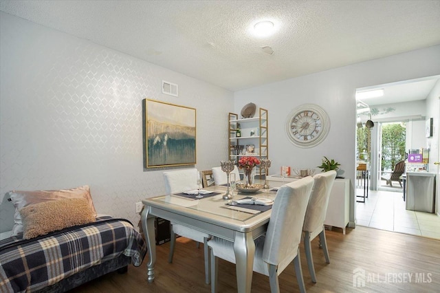 dining room with a textured ceiling, visible vents, and wood finished floors