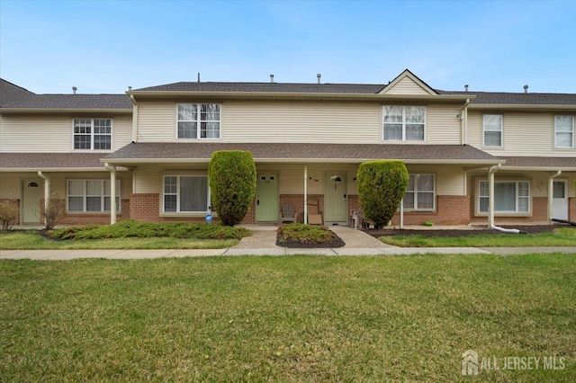 townhome / multi-family property with brick siding and a front yard