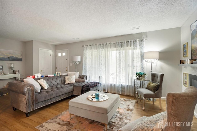living area with a wealth of natural light, a textured ceiling, and wood finished floors