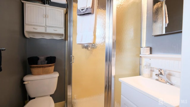 bathroom with a shower stall, toilet, and vanity