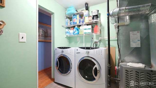 clothes washing area featuring washing machine and dryer, wood finished floors, and laundry area