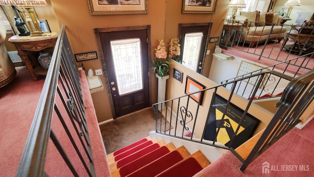 carpeted foyer entrance with baseboards and stairway