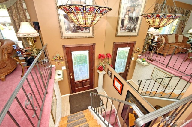 carpeted entryway featuring stairway, baseboards, and a chandelier