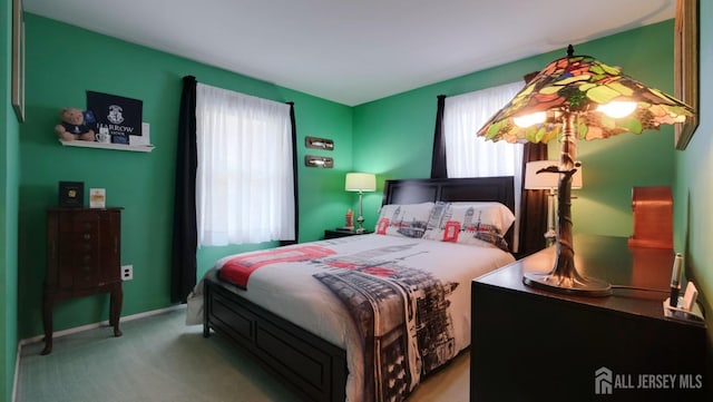 carpeted bedroom featuring baseboards and multiple windows