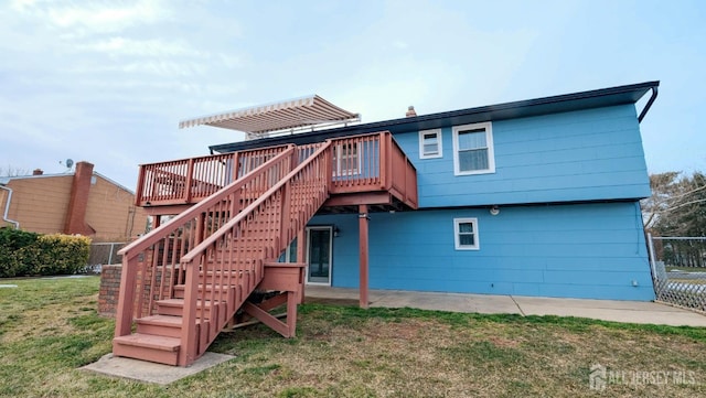 back of property with a wooden deck, fence, a yard, and stairs