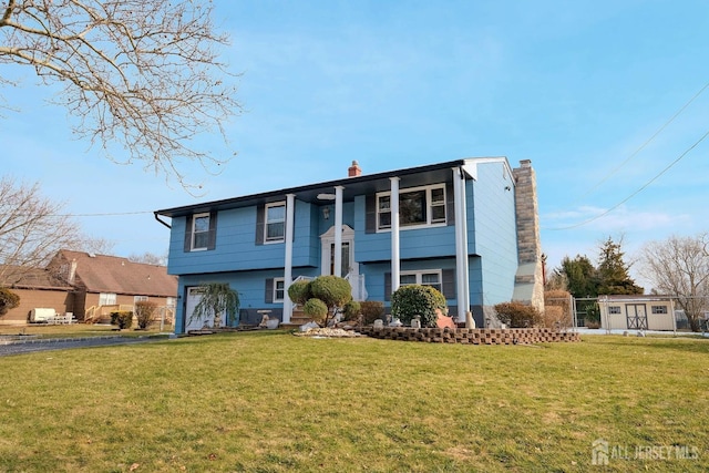 raised ranch with a chimney, driveway, a garage, and a front yard