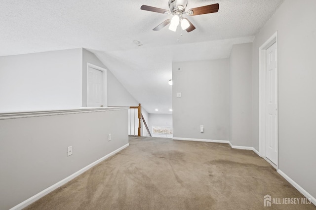 additional living space with carpet floors, ceiling fan, a textured ceiling, and baseboards