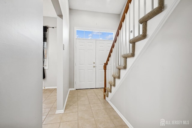 entrance foyer with stairs, light tile patterned flooring, and baseboards