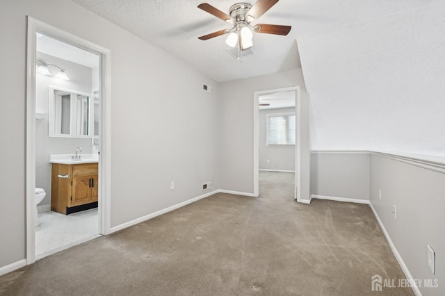 carpeted empty room with visible vents, baseboards, ceiling fan, a textured ceiling, and a sink