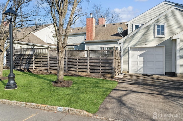 view of yard featuring a garage, driveway, and fence