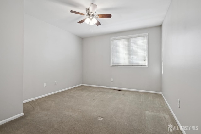 spare room with ceiling fan, carpet flooring, visible vents, and baseboards