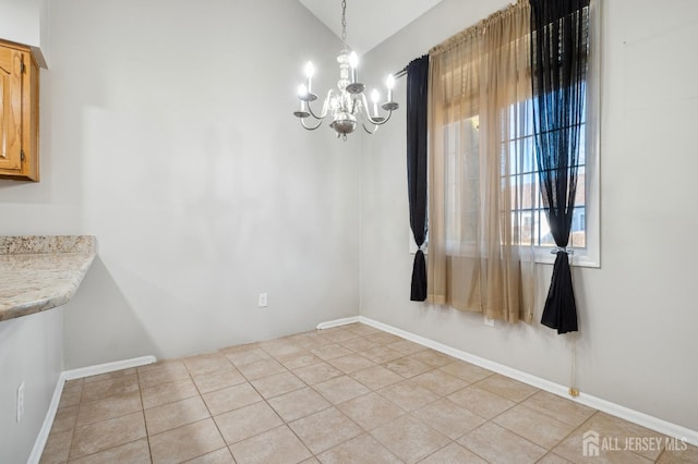 unfurnished dining area with lofted ceiling, light tile patterned flooring, baseboards, and a notable chandelier