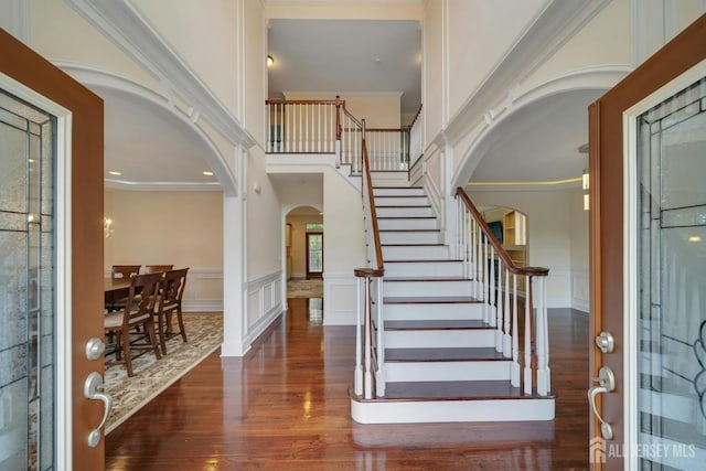 foyer with a high ceiling, ornamental molding, and dark hardwood / wood-style flooring