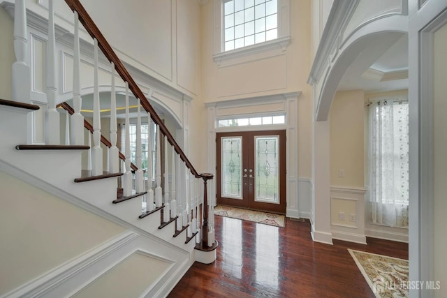 entryway with a towering ceiling, french doors, and dark hardwood / wood-style flooring