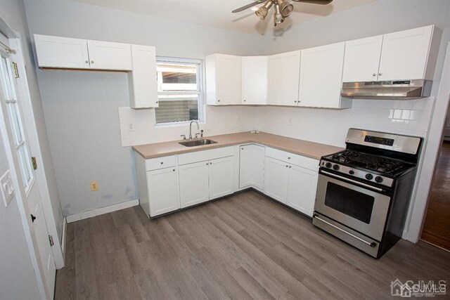 kitchen featuring ceiling fan, light wood-type flooring, stainless steel gas stove, white cabinets, and sink