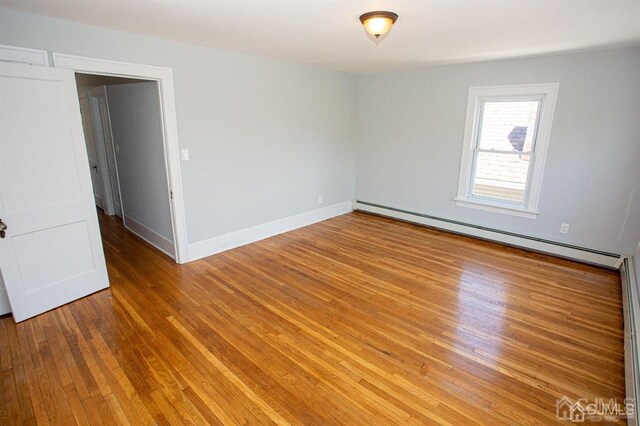 empty room with a baseboard heating unit and hardwood / wood-style flooring