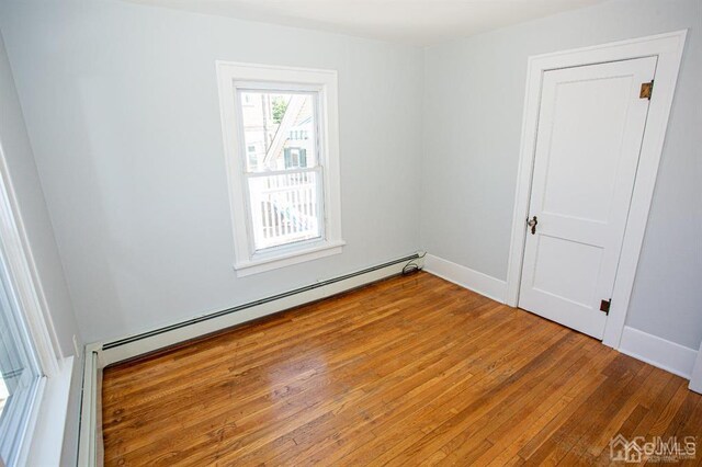 spare room with baseboard heating and hardwood / wood-style floors