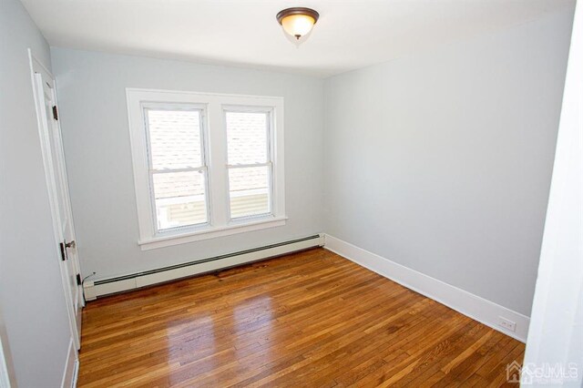 empty room featuring a baseboard heating unit and light hardwood / wood-style floors