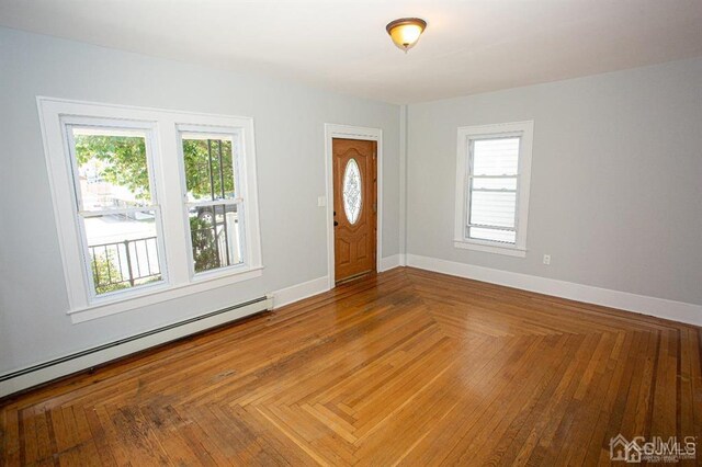 foyer with a healthy amount of sunlight, a baseboard heating unit, and parquet flooring