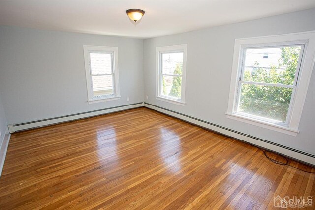 unfurnished room featuring hardwood / wood-style floors and a baseboard radiator