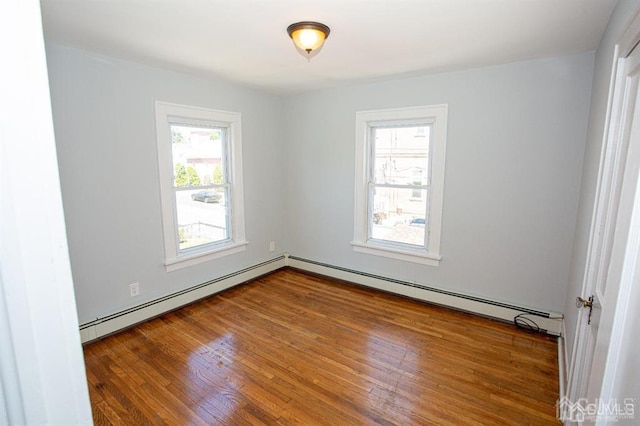 unfurnished room with baseboard heating and hardwood / wood-style flooring