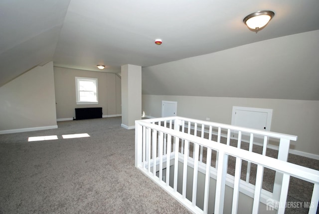 additional living space featuring baseboards, vaulted ceiling, and carpet flooring