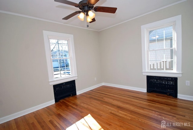 unfurnished room with radiator, crown molding, baseboards, and wood finished floors