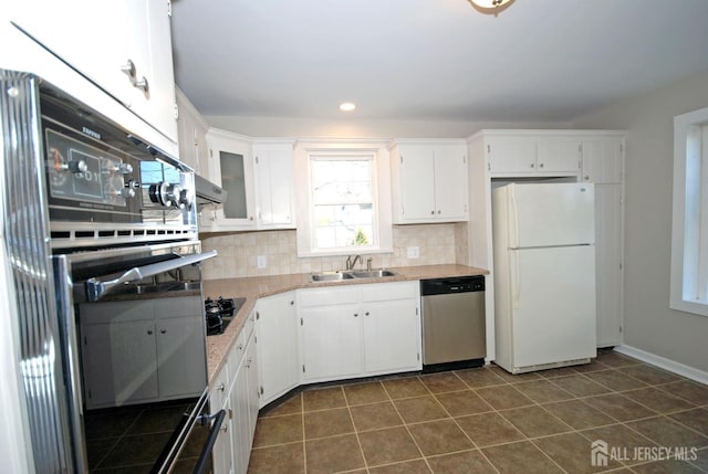 kitchen featuring white cabinets, backsplash, freestanding refrigerator, stainless steel dishwasher, and a sink