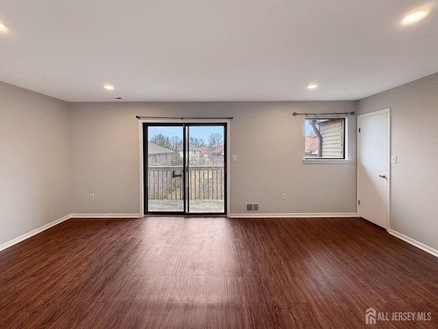 unfurnished room featuring dark wood-style floors, a healthy amount of sunlight, and visible vents