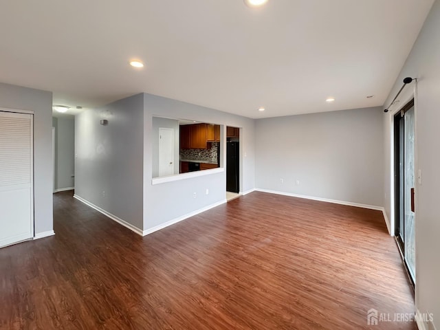 empty room featuring dark wood-type flooring, recessed lighting, and baseboards