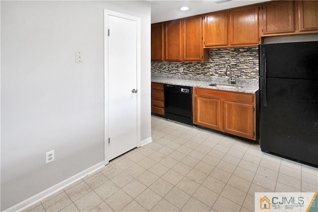 kitchen featuring a sink, baseboards, backsplash, black appliances, and brown cabinetry