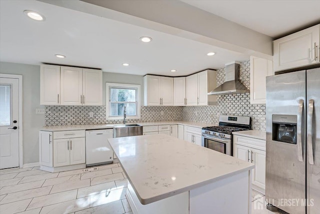 kitchen with stainless steel appliances, light stone countertops, wall chimney exhaust hood, and white cabinetry