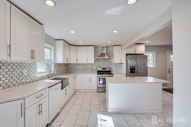 kitchen featuring stainless steel appliances, white cabinetry, decorative backsplash, sink, and wall chimney exhaust hood