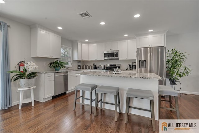 212 Freeman St, Woodbridge Proper, NJ 07095 - kitchen featuring appliances with stainless steel finishes, a kitchen bar, white cabinets, a center island, and dark wood-style flooring