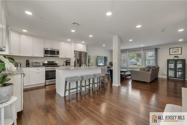 212 Freeman St, Woodbridge Proper, NJ 07095 - kitchen with appliances with stainless steel finishes, open floor plan, white cabinets, a kitchen breakfast bar, and a kitchen island