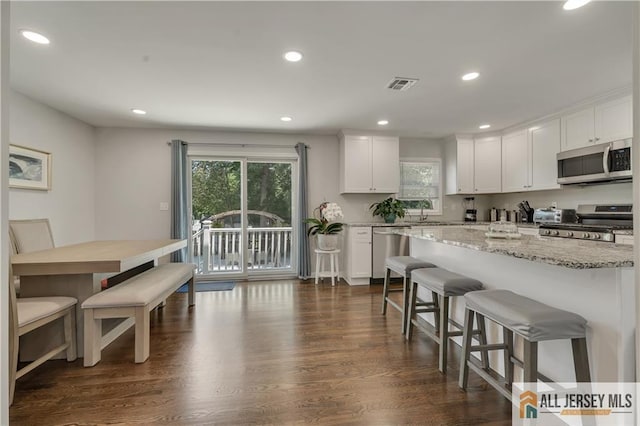 212 Freeman St, Woodbridge Proper, NJ 07095 - kitchen with appliances with stainless steel finishes, a breakfast bar area, white cabinets, recessed lighting, and dark wood-style flooring