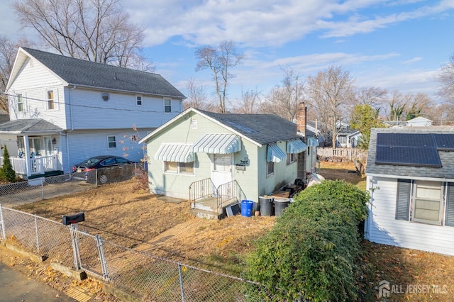 136-136 Hilltop Blvd, Old Bridge, NJ 07735 - rear view of house featuring a fenced backyard, a gate, roof mounted solar panels, and a residential view