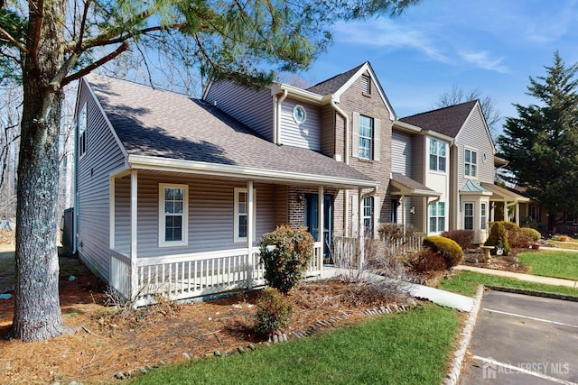 traditional-style house with a porch and roof with shingles